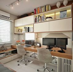 a home office with two computer desks and bookshelves on the wall above it