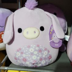 there is a pink pig stuffed animal on the shelf with other stuffed animals behind it