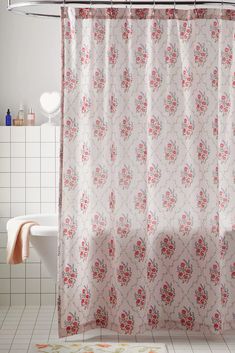 a bathroom with a pink shower curtain next to a white bath tub and toilet paper