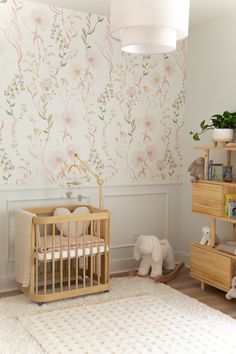 a baby's room with floral wallpaper and wooden furniture