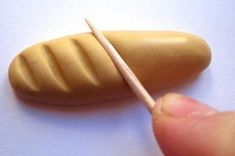 a hand holding a toothpick over a peanut on a white surface with other items in the background