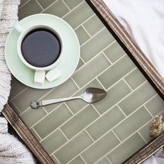 a cup of coffee and spoon on a tray