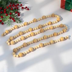 several wooden beads on a table next to a christmas tree and presents with red berries