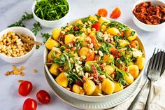 a white bowl filled with salad next to bowls of beans and tomatoes on a table