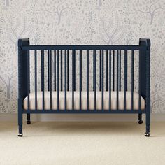 a baby crib in front of a wall with trees on it