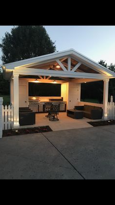 an outdoor living area with a grill and dining table in the middle of it at night