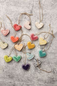 heart shaped ceramic ornaments hanging from twine on concrete surface, with string attached to each ornament