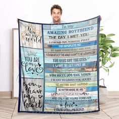 a man holding up a blanket with words on it