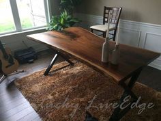 a wooden table sitting on top of a rug in a living room next to a guitar