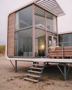 a small wooden structure sitting on top of a sandy beach next to the ocean with stairs leading up to it