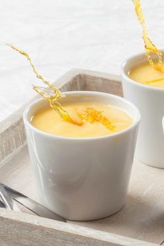 two white bowls filled with soup on top of a wooden tray