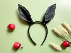 an overhead view of a black bunny ears headband with cherries on the side