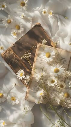 an open book laying on top of white flowers