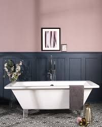 a bath tub sitting next to a toilet in a room with pink walls and flooring