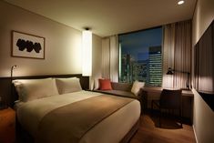 a hotel room with a bed, desk and chair in front of a large window