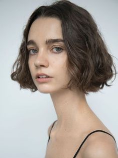 a woman with short hair and blue eyes is looking at the camera while wearing a black top