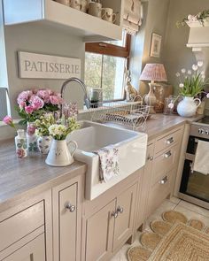 a kitchen with white cabinets and pink flowers in vases on the sink counter top