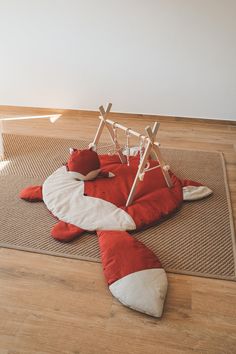 a red and white stuffed animal laying on top of a rug