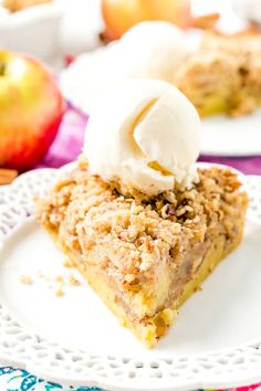 a slice of apple crumb pie on a plate with whipped cream and apples in the background