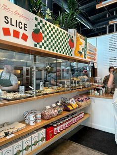 people are standing at the counter of a restaurant with many items on display in front of them