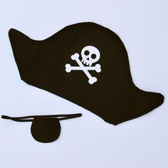 a black pirate hat with a skull and crossbones on it, sitting next to a pair of scissors