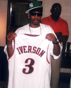 a man holding up a jersey with the number 3 on it in front of him