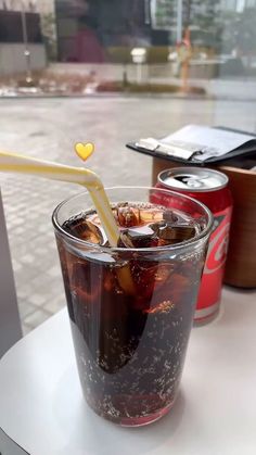 there is a drink with a straw in it on the table next to two soda cans