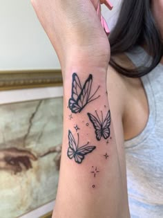 a woman's arm with three butterflies on it and stars in the sky above her