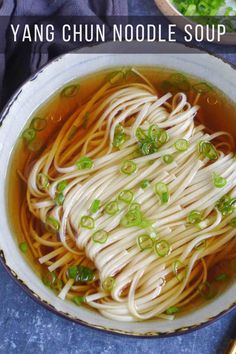 a bowl filled with noodles and vegetables on top of a blue table cloth next to chopsticks