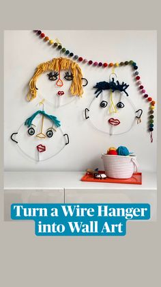 two paper faces are hanging on the wall next to a coffee cup and bowl with yarn