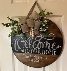 a welcome sign hanging on the front door with burlocks and greenery around it