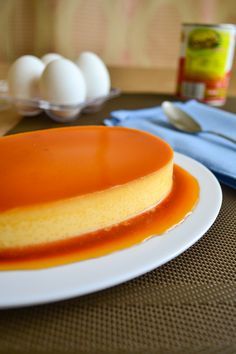 an orange and yellow dessert on a white plate next to some eggs in a container