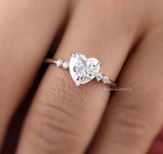 a woman's engagement ring with a heart shaped diamond on the middle and side