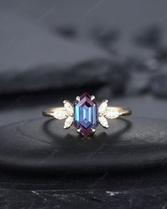 an image of a ring that is on top of a black stone surface with white and blue stones