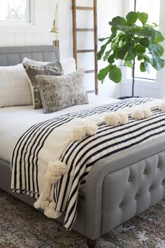 a bed with black and white striped sheets, pillows and blankets on top of it