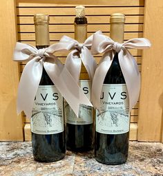 two bottles of wine with bows tied around them sitting on a counter top next to each other