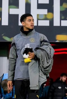 a man holding a stuffed animal in his right hand while standing on a soccer field