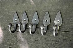 five metal hooks hang on a wooden wall