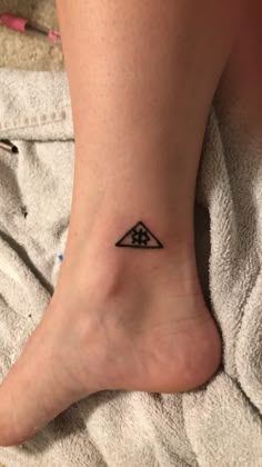 a woman's foot with a small triangle tattoo on it