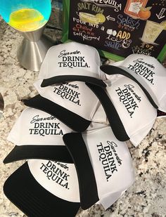 five hats are sitting on the counter next to a drink menu and a cocktail shaker