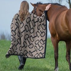 a woman walking with a horse wrapped in a blanket