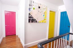 there are three doors in the hallway and one is painted bright pink, yellow, and blue