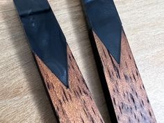 two pieces of wood sitting next to each other on top of a wooden table with black handles