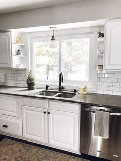 a clean kitchen with white cabinets and stainless steel dishwasher on the countertop