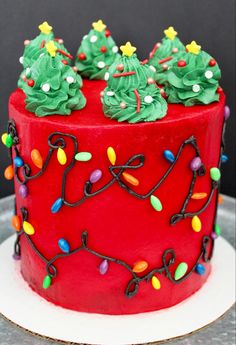 a red cake decorated with christmas lights and trees