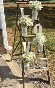 an old ladder is decorated with mason jars and baby's breath flowers to spell out the word love