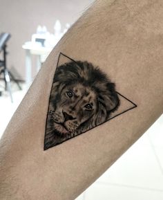 a lion with a triangle tattoo on his leg is shown in black and grey ink