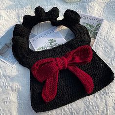 a crocheted purse with a red bow on it sitting on top of a table