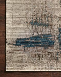 an area rug with blue and white designs on it, sitting on a wooden floor