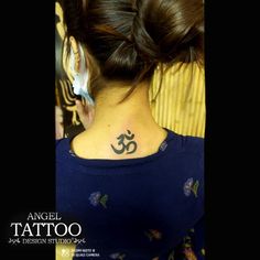 the back of a woman's neck with an om tattoo on her left side